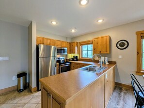 A kitchen with wooden cabinets, stainless steel appliances, a sink, and a window. - Prime Location | Steps to Slopes | King Bed (Keystone)