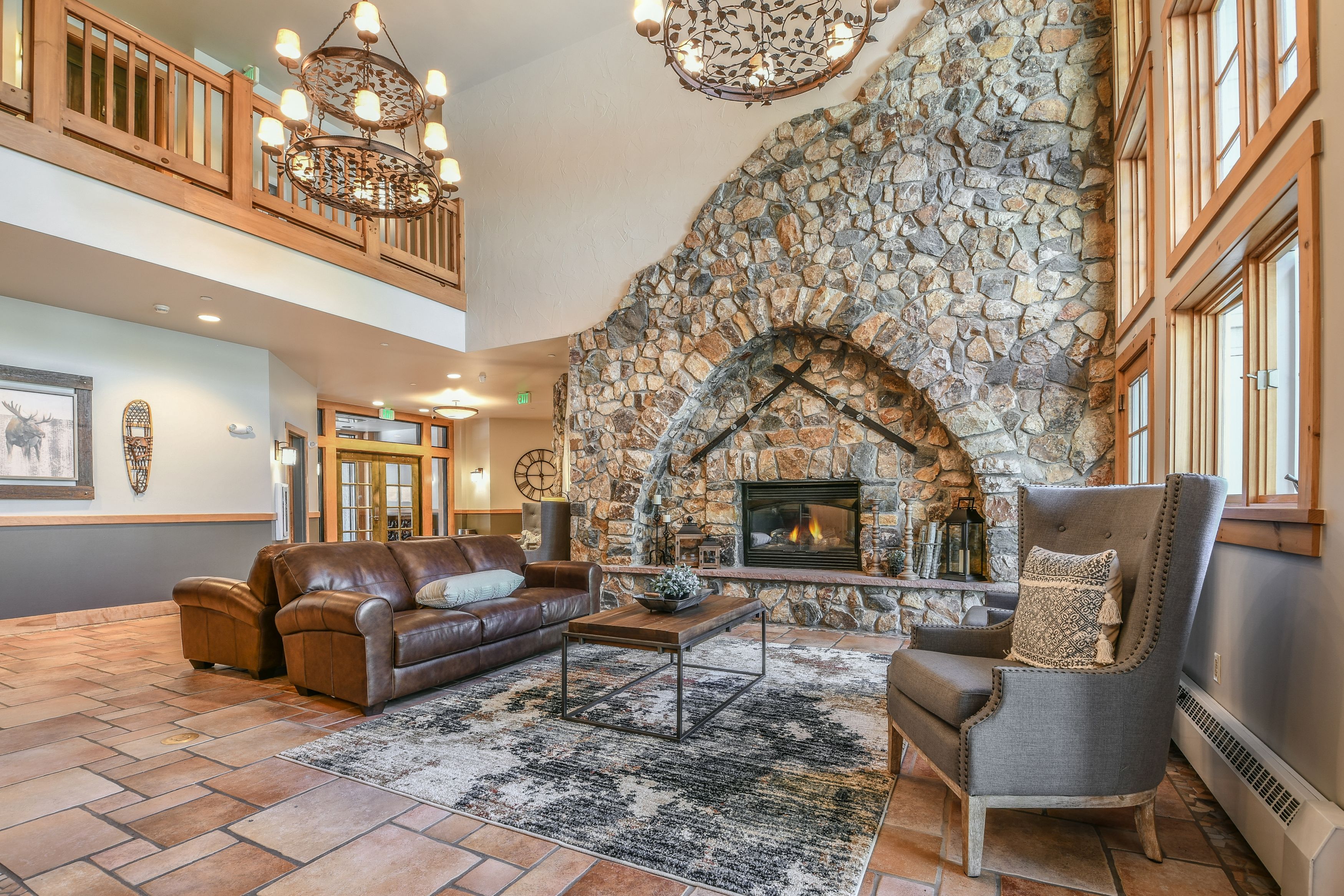 A spacious lobby with a stone fireplace, leather sofas, and a high ceiling with wooden railings.