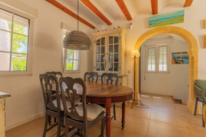 A dining area with a wooden table and chairs, a cabinet with glass doors, and a painting on the wall. - Semi-detached villa in a luxury hotel resort · El Rodat, Jávea (VC)