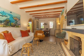 A cozy living room with a sofa, armchairs, a dining table, and a fireplace. - Semi-detached villa in a luxury hotel resort · El Rodat, Jávea (VC)