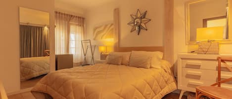 A hotel room with a large bed, a bedside table with a lamp, a chair, and a dresser.