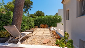 A patio with a chair, a tree, and a stack of logs. - Semi-detached villa in a luxury hotel resort · El Rodat, Jávea (VC)