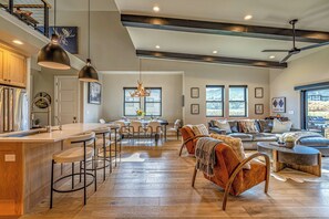A spacious living area with a high ceiling, a dining area with a chandelier, and a kitchen with modern appliances. - Abode at Redemption Ridge, deer valley east, hot tub, game room (Heber City)