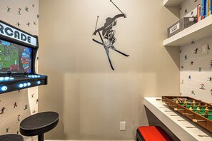 A room with a wall decal of a skier, a foosball table, and a shelf with books. - Abode at Redemption Ridge, deer valley east, hot tub, game room (Heber City)