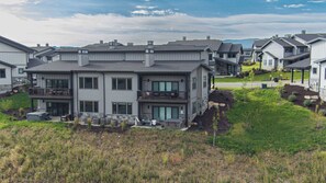 A multi-story residential building with a balcony, outdoor seating, and a landscaped yard. - Abode at Redemption Ridge, deer valley east, hot tub, game room (Heber City)