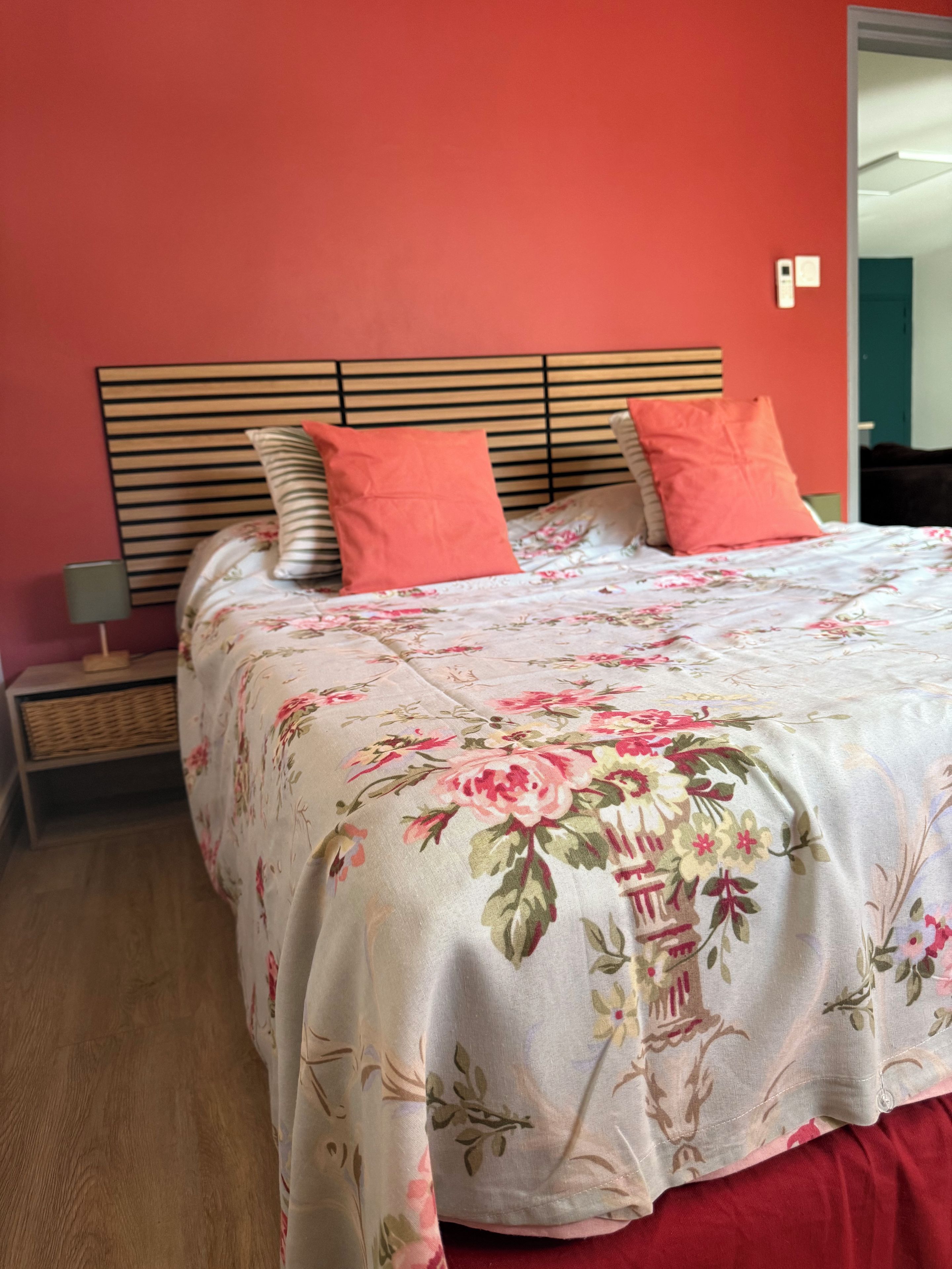 Een bed met een bloemenprint sprei, een houten hoofdbord en twee kussens.
