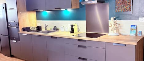 Cozinha moderna com armários cinza, bancada de madeira e parede azul decorativa.