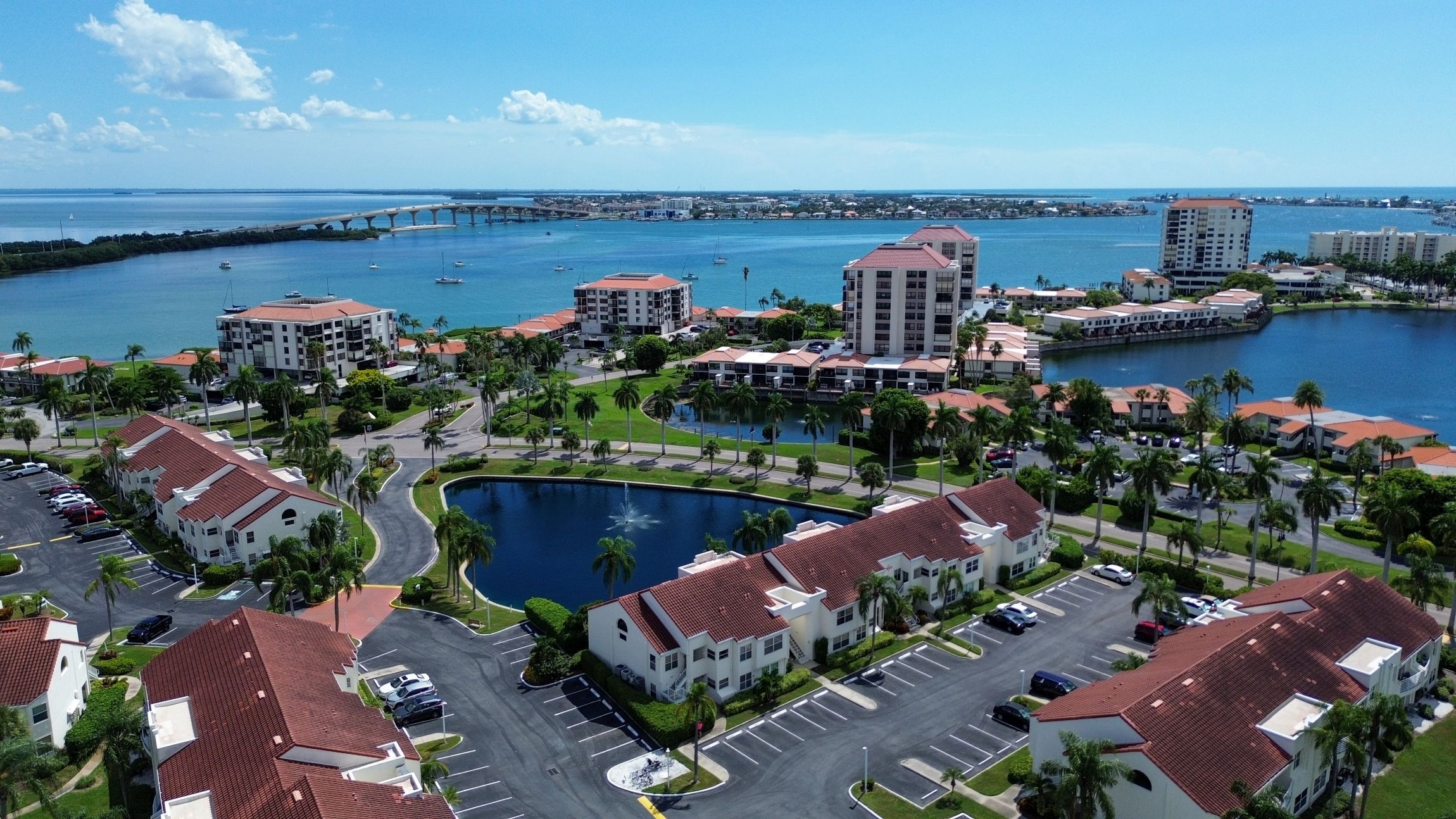 Un quartier résidentiel situé sur la côte, comprenant plusieurs immeubles, une marina et une vaste étendue d’eau.