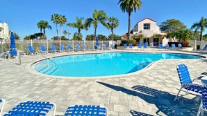 Una piscina con sedie blu e palme.