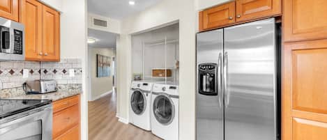 A modern kitchen with stainless steel appliances, wooden cabinets, and a tiled backsplash.