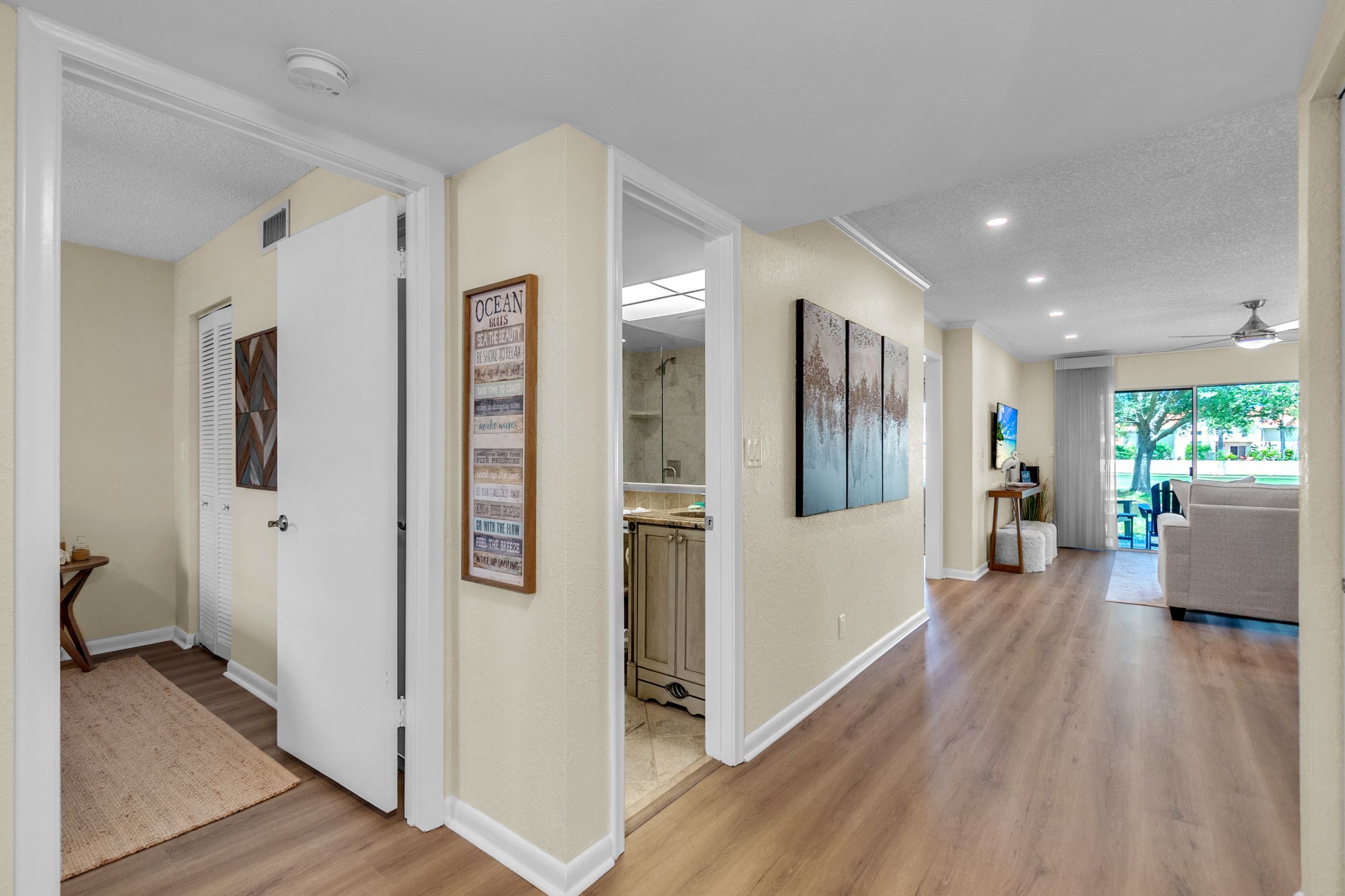 A spacious hallway with wooden flooring, white walls, and a ceiling fan.