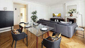 Un salon moderne avec un coin repas, un canapé gris et une cheminée.