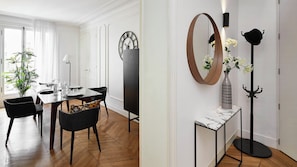 Een eethoek met een houten visgraatvloer, een voor vier gedekte eettafel en zwarte stoelen.