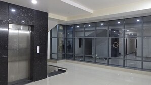 A spacious lobby with a modern elevator and glass walls.