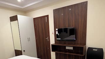 Habitación de hotel con cama, armario, espejo, televisor y escritorio.