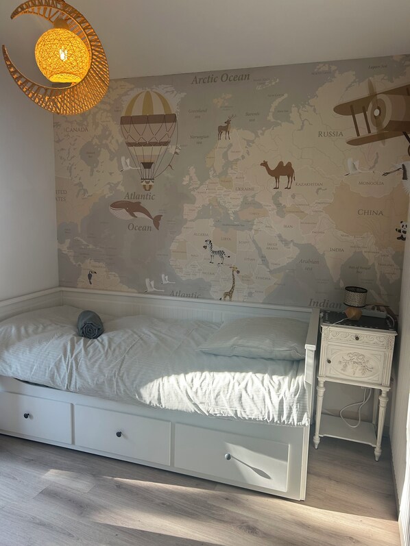A bedroom with a bed, a nightstand, and a wall map.