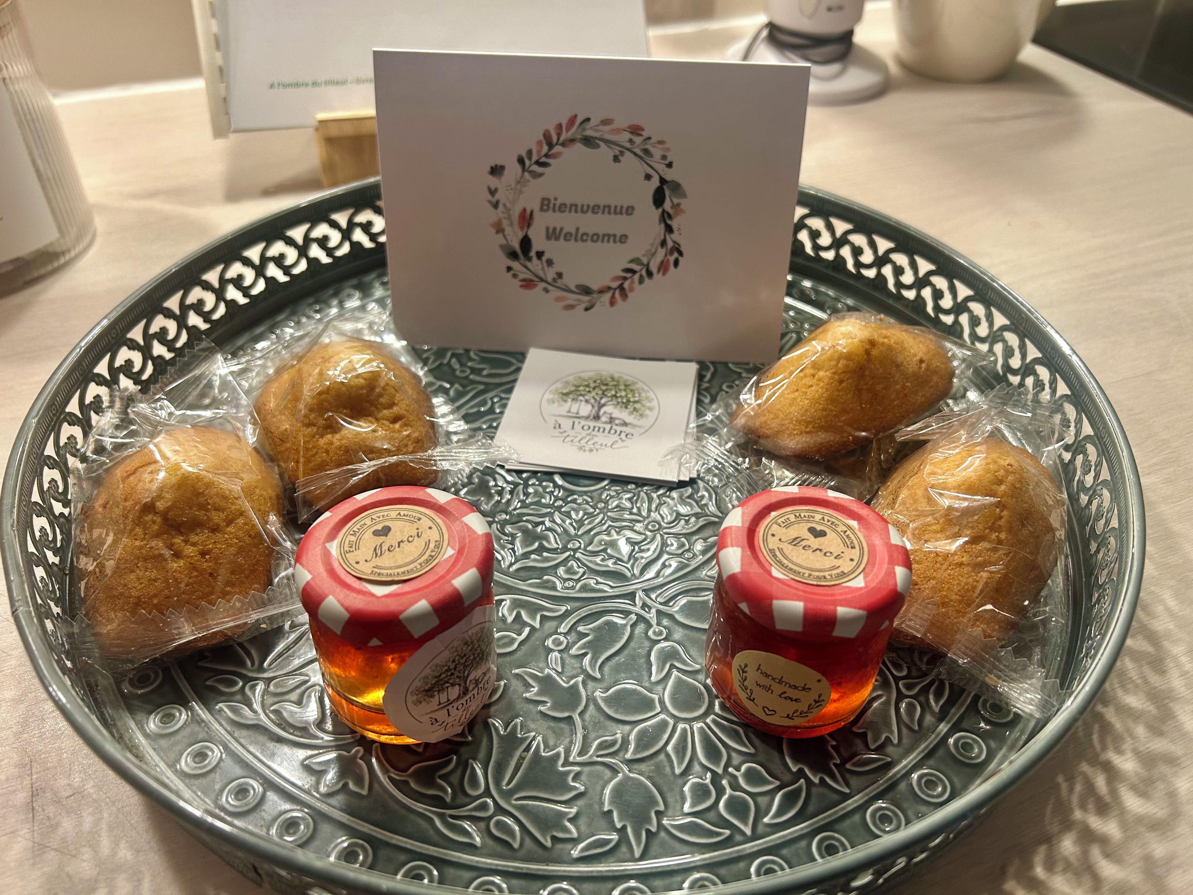 A decorative plate with pastries and two small jars of jam, accompanied by a welcome card.