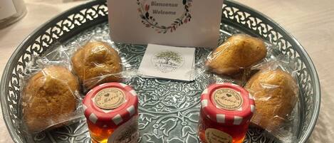 A decorative plate with pastries and two small jars of jam, accompanied by a welcome card.