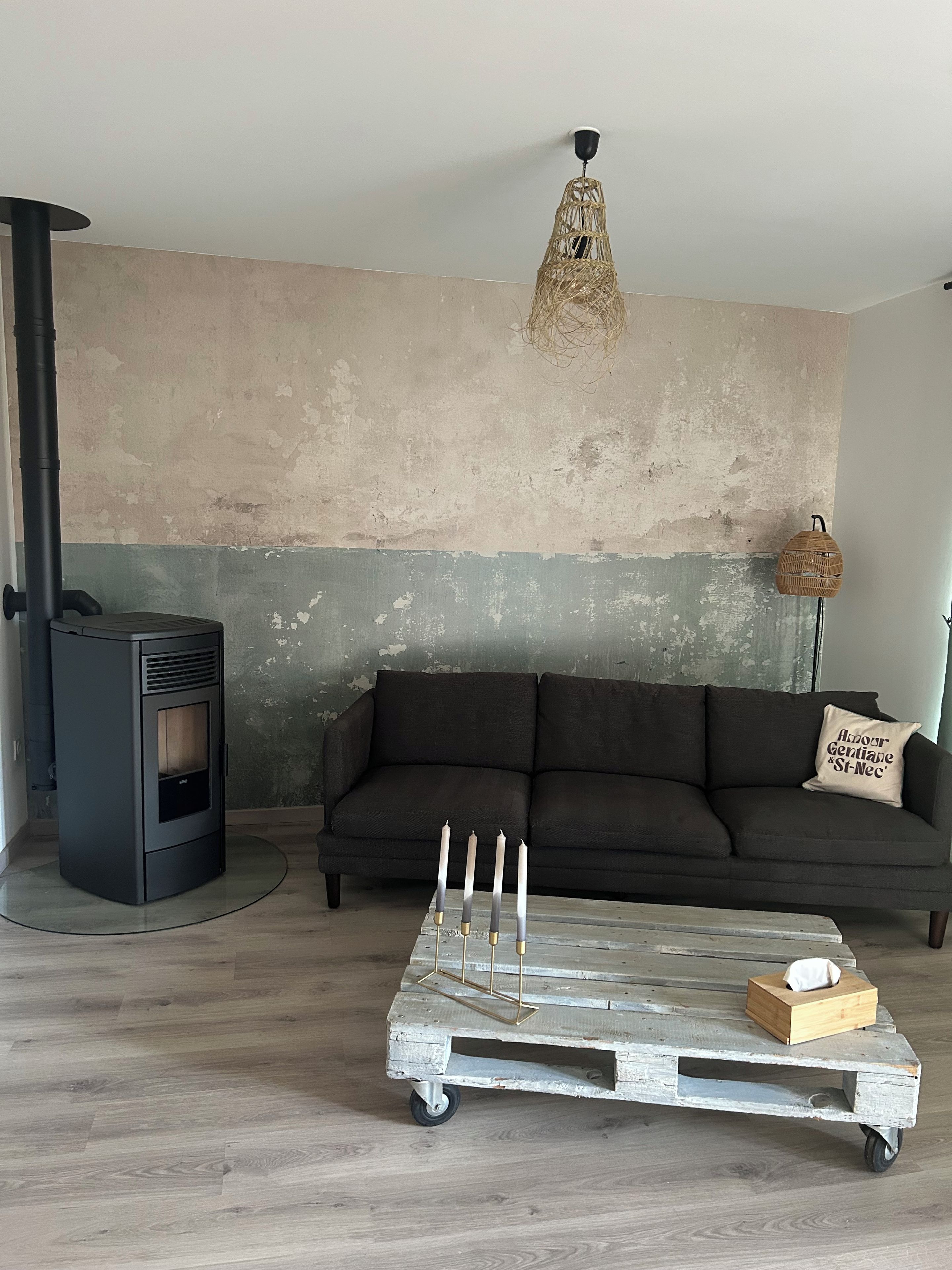 Una sala de estar con un sofá, una mesa de centro de madera con velas, una lámpara de pared y una chimenea.