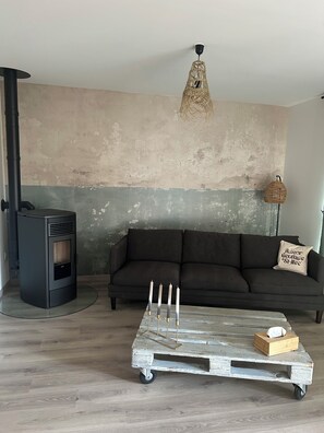 A living room with a sofa, a wooden coffee table with candles, a wall-mounted lamp, and a fireplace.