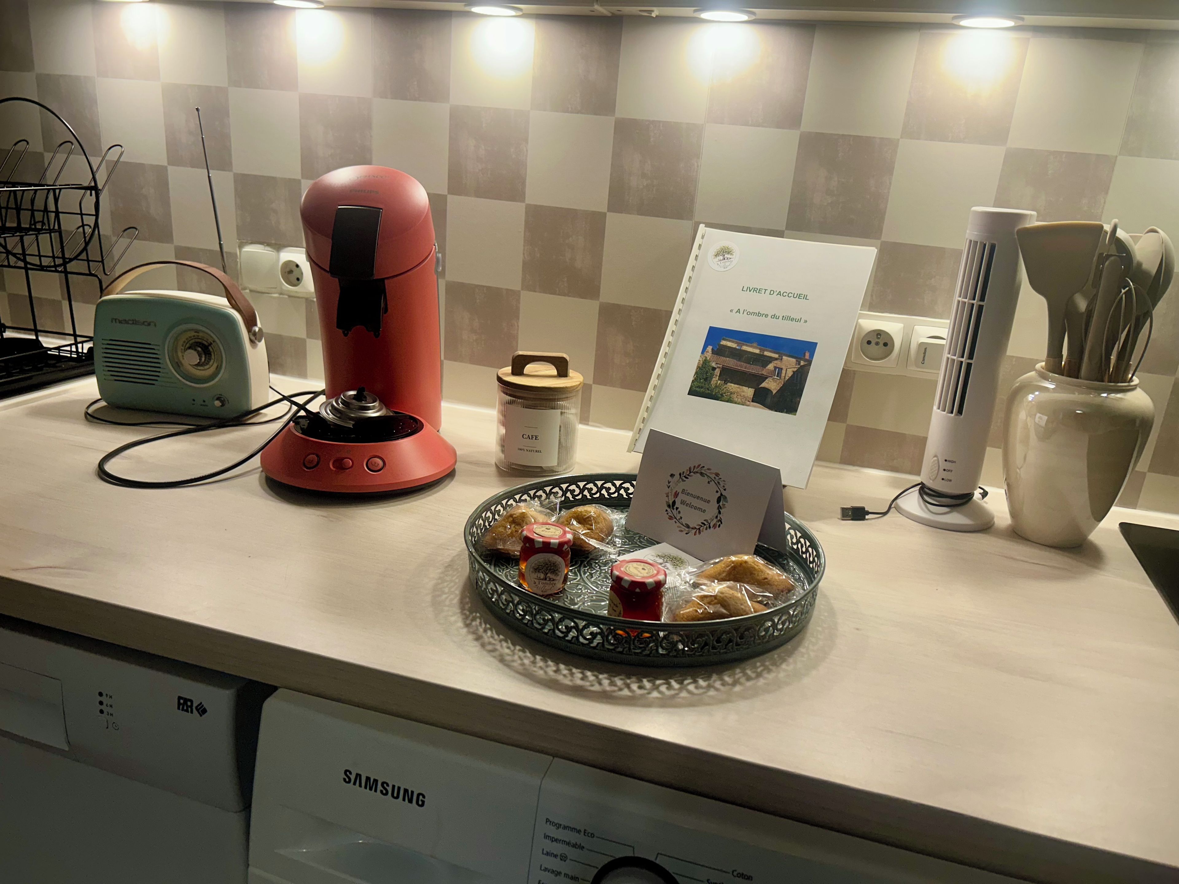 A kitchen counter with a coffee maker, a rice cooker, a rice cooker basket, a rice cooker basket with a card, a rice cooker basket with a card, a rice cooker basket with a card, a rice cooker basket with a card, a rice cooker basket with a card, a rice cooker basket with a card, a rice cooker basket with a card, a rice cooker basket with a card, a rice cooker basket with a card, a rice cooker basket with a card, a rice cooker basket with a card, a rice cooker basket with a card, a rice cooker basket with a card, a rice cooker basket with a card, a rice cooker basket with a card, a rice cooker basket with a card, a rice cooker basket with a card, a rice cooker basket with a card, a rice cooker basket with a card, a rice cooker basket with a card, a rice cooker basket with a card, a rice cooker basket with a card, a rice cooker basket