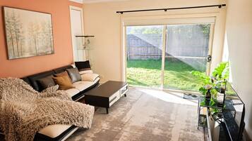 A living room with a sofa, coffee table, and a glass cabinet with plants.