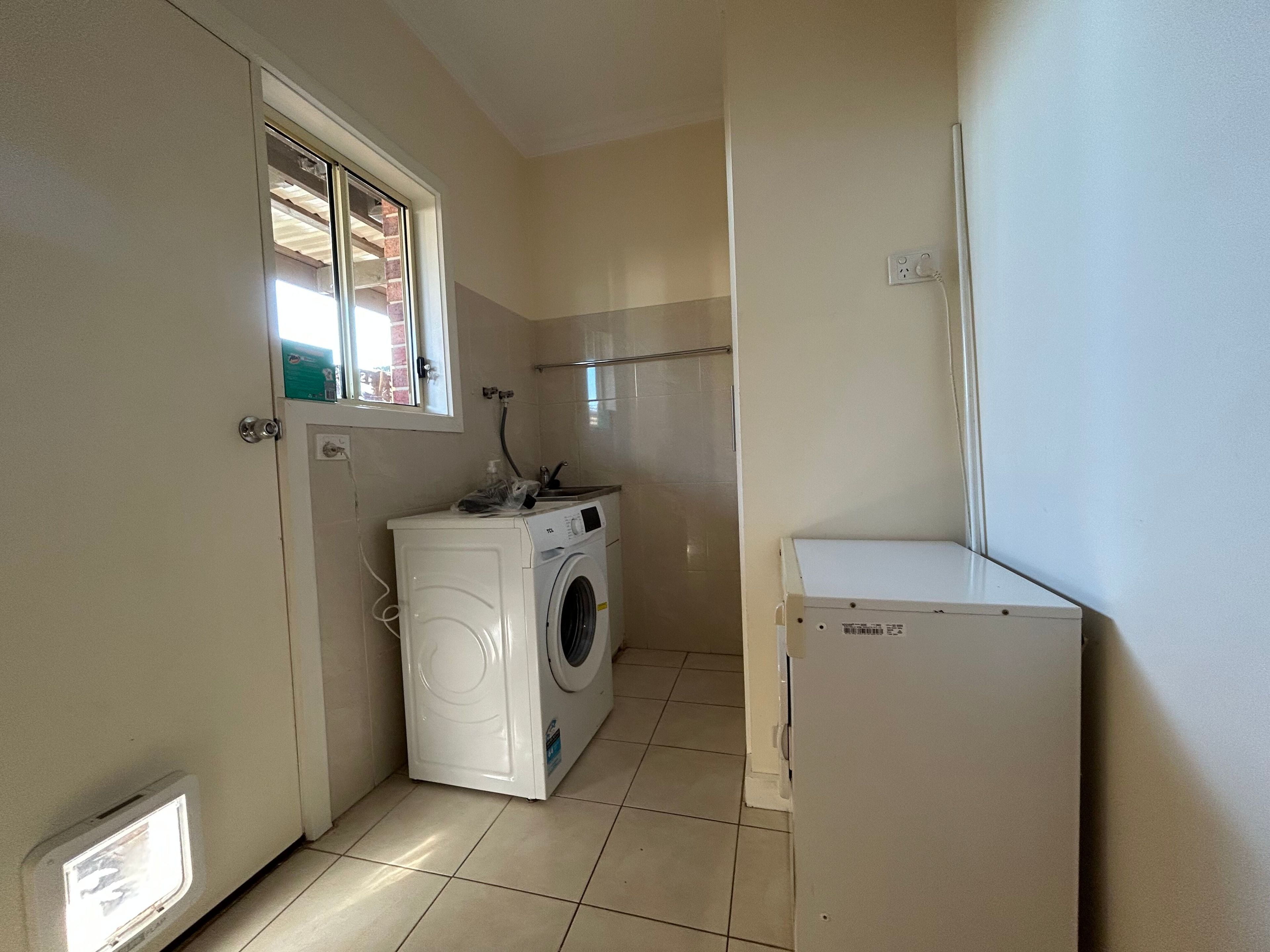 A laundry room with a washing machine, a dryer, and a small refrigerator.