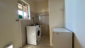 Un lavadero con lavadora, secadora y un refrigerador pequeño.
