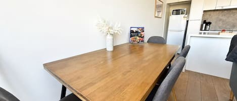 Une cuisine moderne avec une table à manger en bois, des chaises et un réfrigérateur.