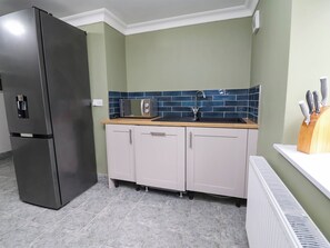 Eine Küche mit einem Edelstahl-Kühlschrank, einer Mikrowelle, einem Spülbecken mit Wasserhahn und Schränken.
