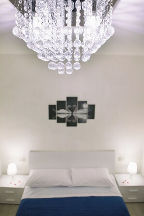 Ein Schlafzimmer mit einem Bett, Nachttischen, einer Chandelier und einem Wandbild.
