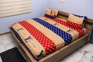 A bed with a patterned bedspread and matching pillows, a wooden headboard, and a marble floor. - Pleasant 1-bedroom Queen with AC in vibrant Koforidua (Koforidua)