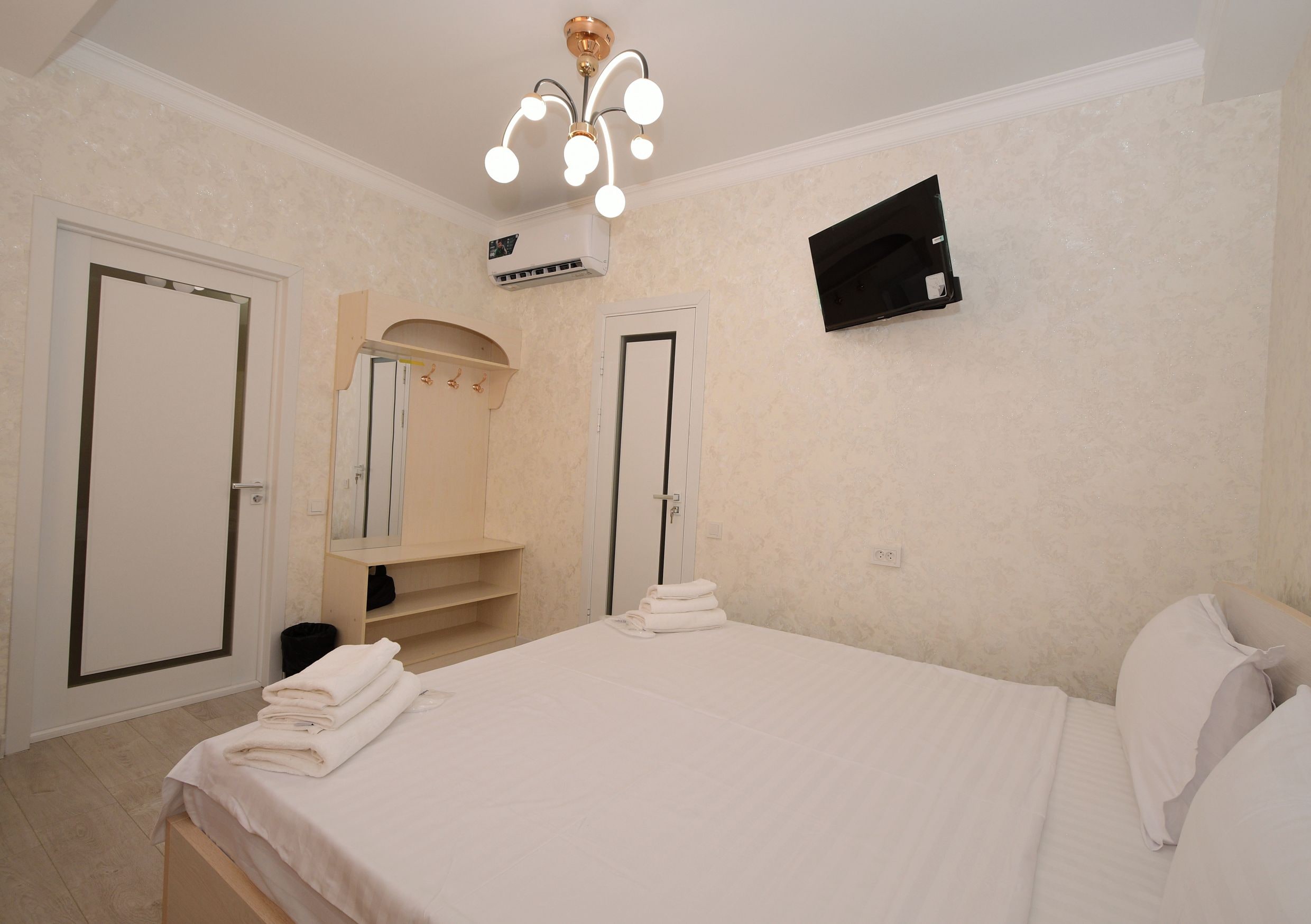 A hotel room with a bed, a TV mounted on the wall, and a ceiling light fixture.