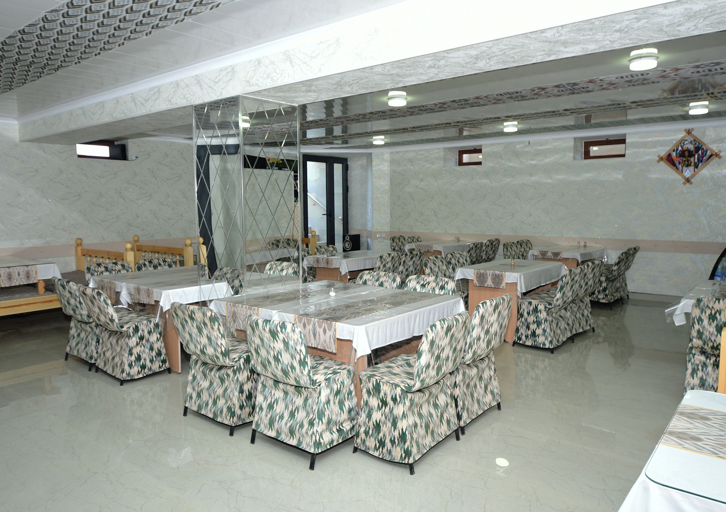 Uma sala de jantar com várias mesas e cabines, piso de mármore e teto alto com padrão geométrico.