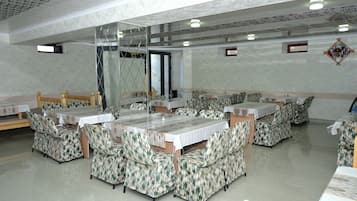 Uma sala de jantar com várias mesas e cabines, piso de mármore e teto alto com padrão geométrico.