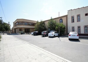 A street view with parked cars, a building with arched windows, and a clear sky.
