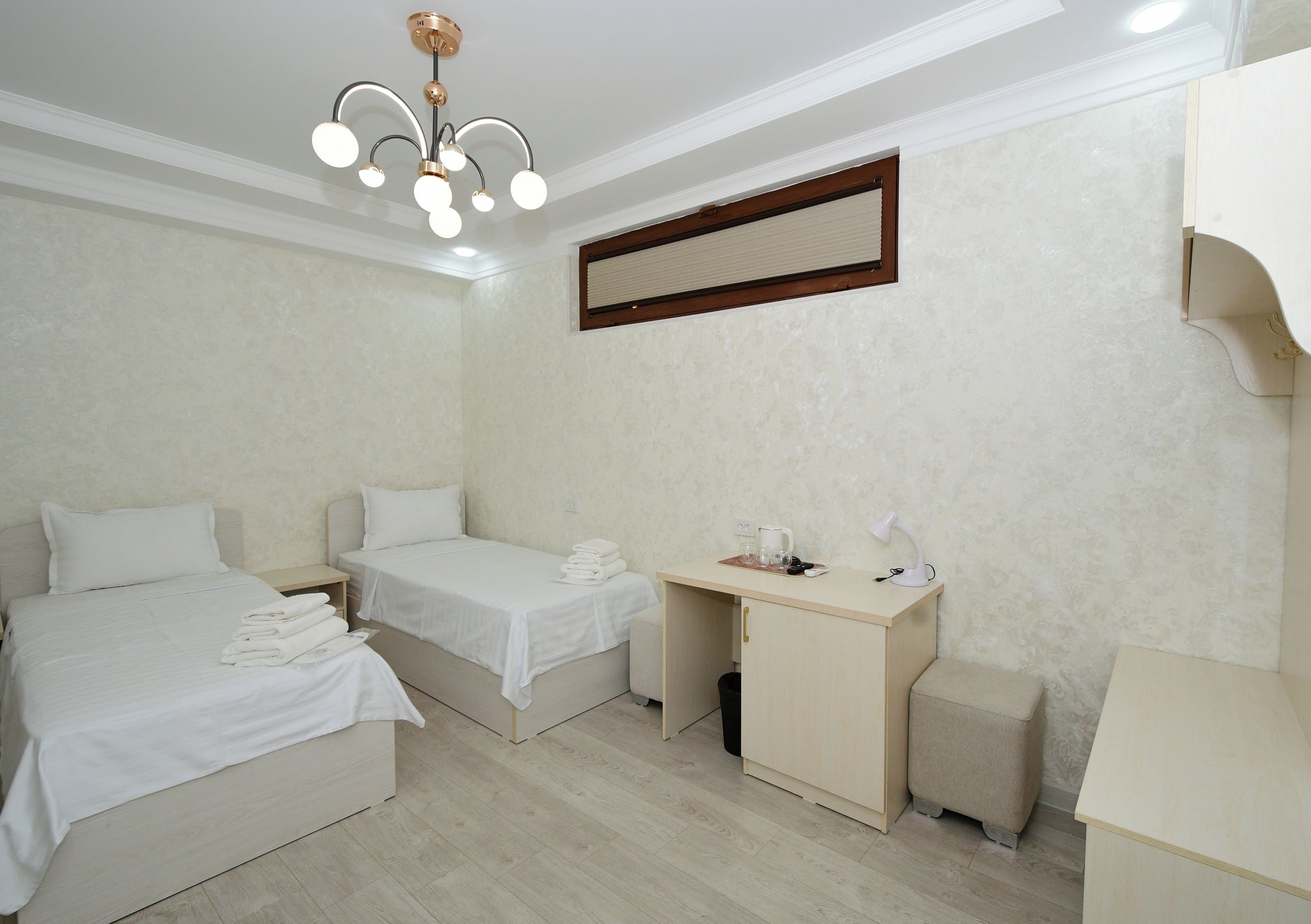 Habitación de hotel con dos camas, un escritorio, una silla, una lámpara y una luminaria en el techo.