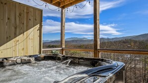 Ein Whirlpool mit einer Holterrasse und Blick auf die Berge.