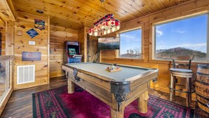 Ein Holzinterieur mit einem Billardtisch, einem Barhocker und einem Wandfernseher.