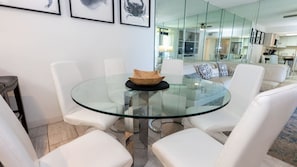 A modern living room with a glass table, white leather chairs, and a sofa with patterned cushions. - Sea Vista Beachfront 3br - Heated Pool 3 Bedroom Apts (South Padre Island)