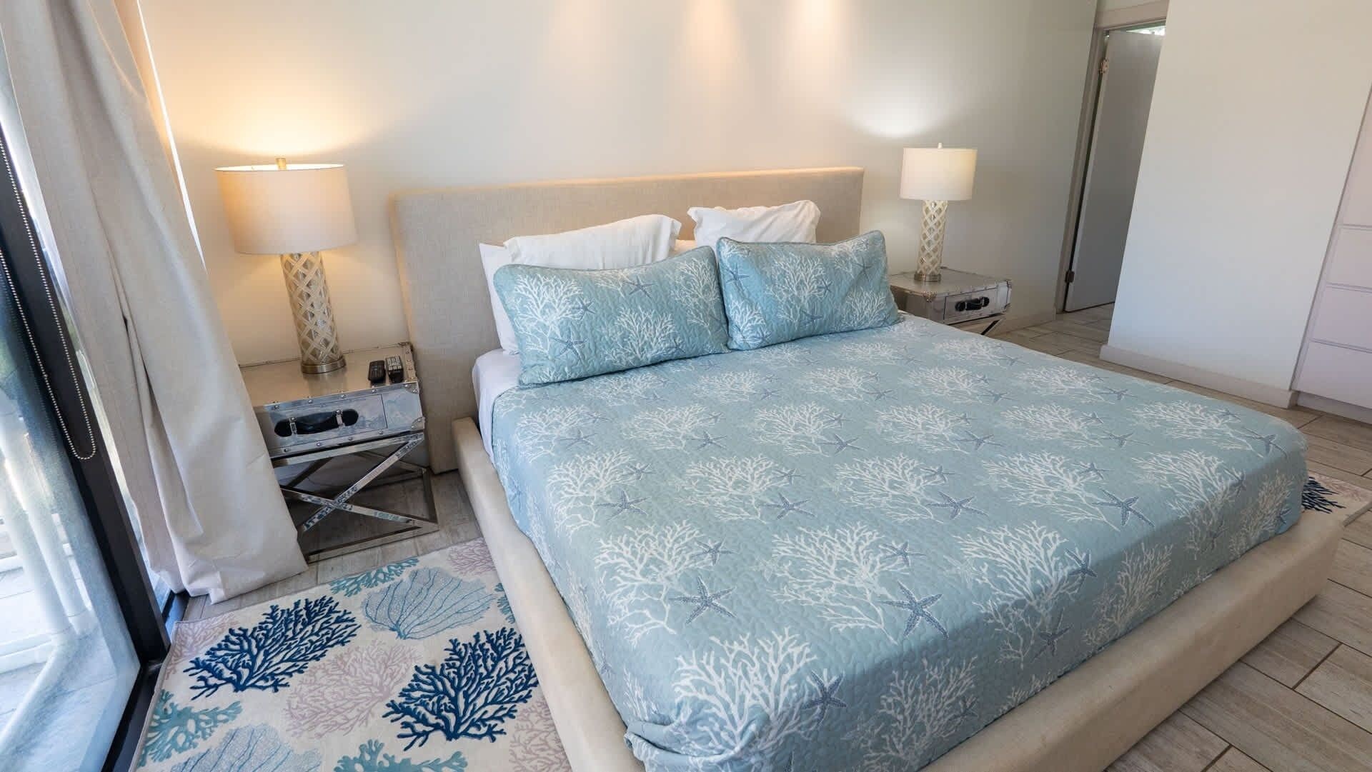 Habitación de hotel con cama, dos mesitas de noche, una lámpara y una ventana con cortinas.
