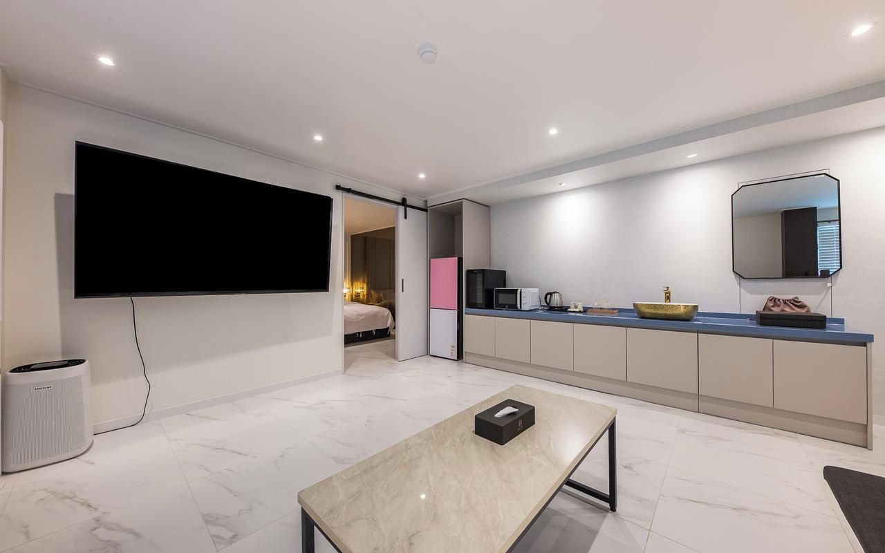 A modern kitchen with a flat-screen TV, a dining table, and a kitchen island.