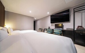 Habitación de hotel moderna con una cama grande, un escritorio con dos sillas, un televisor de pantalla plana y un minibar.