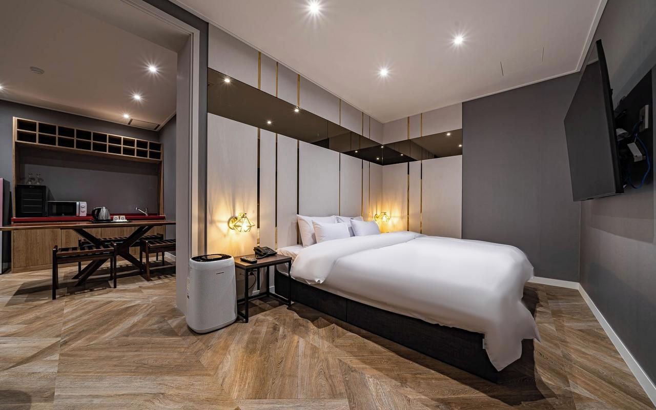 A modern bedroom with a large bed, bedside lamps, and a built-in TV.