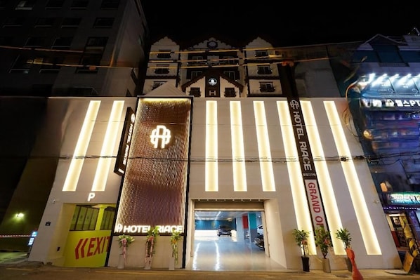 A hotel entrance with a prominent sign, a reception desk, and a parking area. - Hotel RIACE (Suwon)