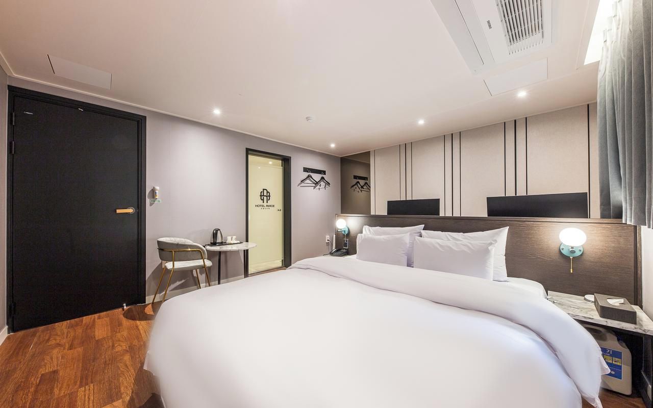 A hotel room with a large bed, bedside tables, a desk, and a chair.