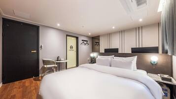 A hotel room with a large bed, bedside tables, a desk, and a chair.