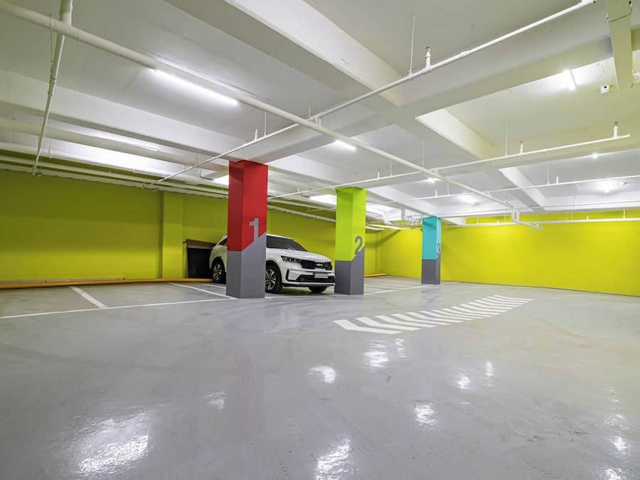 Un aparcamiento de varios niveles con plazas de estacionamiento claramente señalizadas y un coche blanco estacionado en una de ellas.