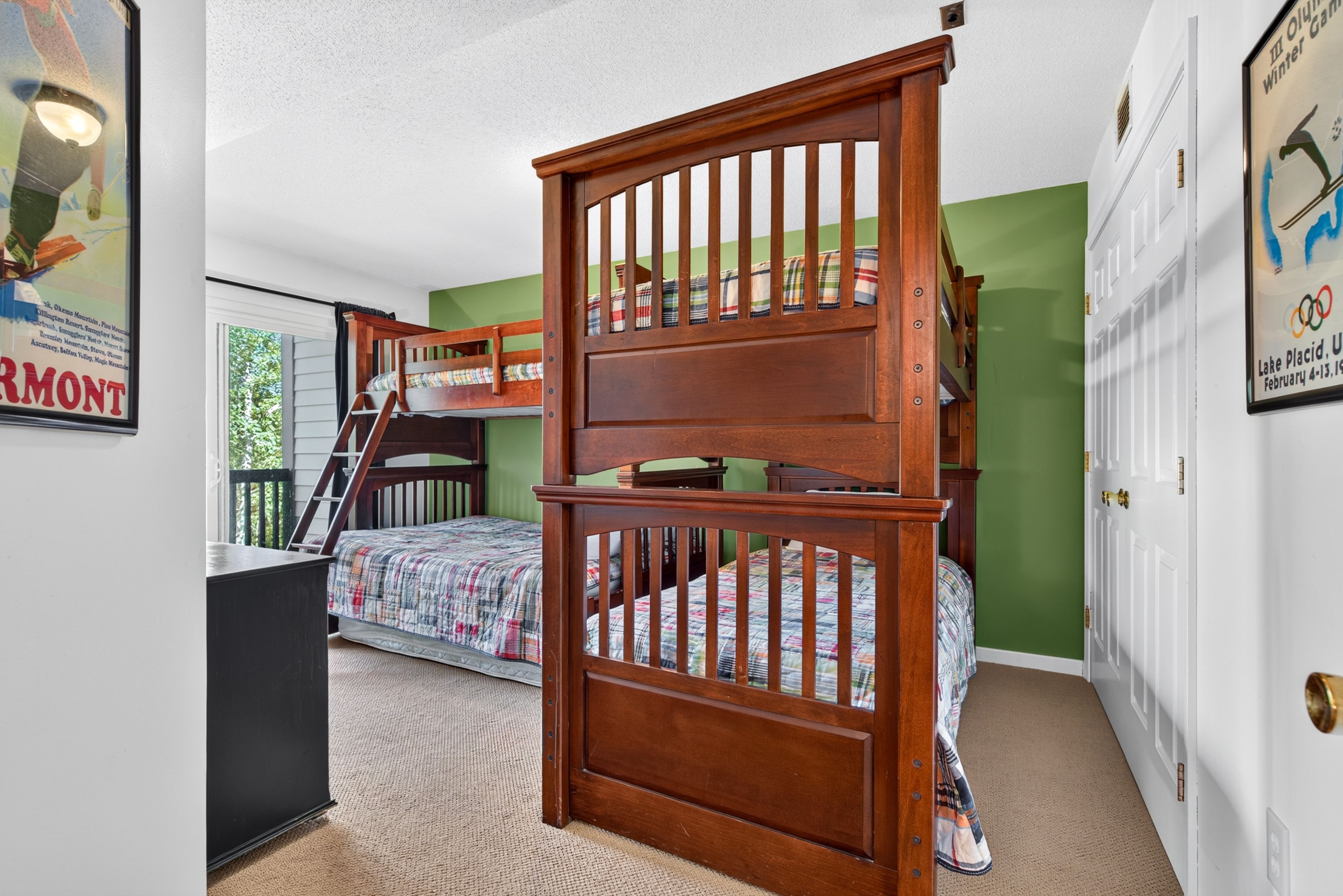A bedroom with bunk beds, a desk, and a dresser.