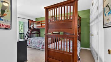 A bedroom with bunk beds, a desk, and a dresser.